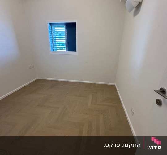 חדר עם רצפת פרקט ודלת לבנה